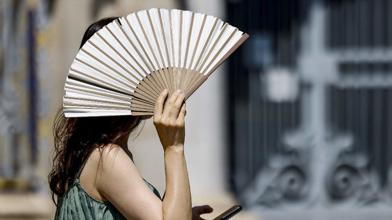 Una mujer se resguarda del sol tras un abanico.EFE